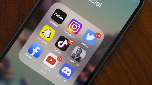 Assorted popular social media apps - BeReal, Instagram, Twitter, Snapchat, TikTok, Clubhouse, Facebook, YouTube, and Discord - are seen on an iPhone. 