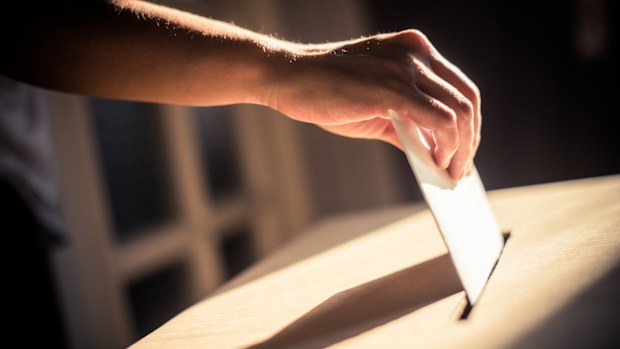 Conceptual image of a person voting, casting a ballot at a polling station, during elections.