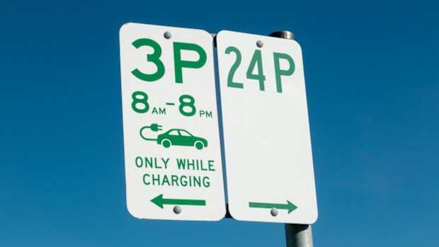 On the left is a sign reserving spaces for electric vehicles and time limits for charging. The sign on the right indicates unlimited parking time of 24 hours. This image was taken at a public carpark next to Heffron sports field, Maroubra, Sydney on a sunny afternoon on 13 April 2025.