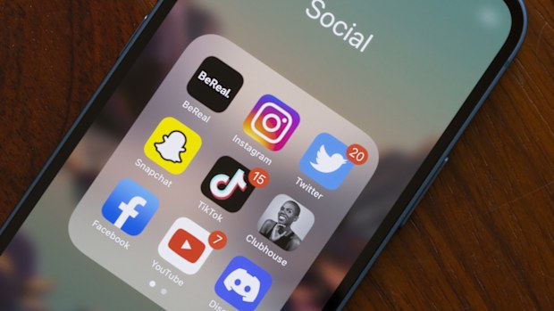 Assorted popular social media apps - BeReal, Instagram, Twitter, Snapchat, TikTok, Clubhouse, Facebook, YouTube, and Discord - are seen on an iPhone. 