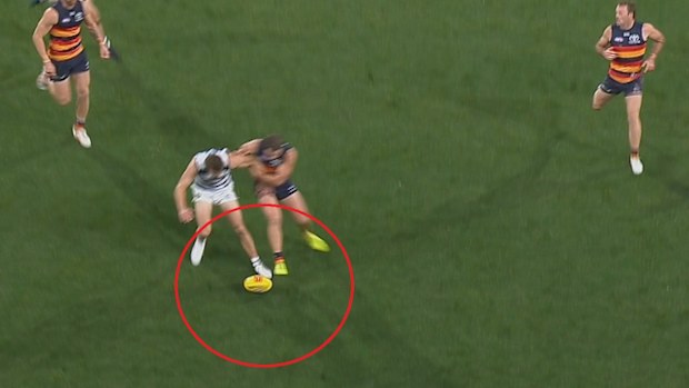 Geelong player Tom Atkins kicks the ball out ahead of Adelaide's Zac Taylor.
