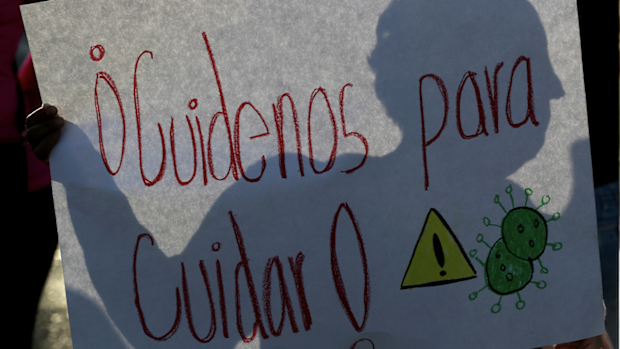 A nurse holds a poster that reads in Spanish Take care us to take care during a protest outside of a public hospital in Mexico City, Monday, April 13, 2020. Public health workers demand more protective gear and training in a protest near a public hospital in the capital. Doctors, nurses and other personnel have demonstrated at a number of public hospitals around Mexico as the coronavirus sickened dozens of medical personnel. (AP Photo/Fernando Llano)
