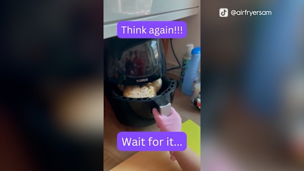 Snapshot of a TikTok video of woman attempting to air fry a whole chicken. Woman sliding air fry container into air fryer.