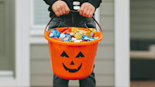 Child in costume holding a Halloween bucket full of sweets
