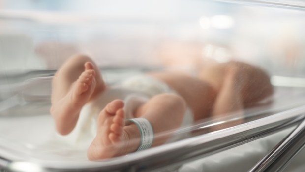 Cute Little Caucasian Newborn Baby Lying in Bassinet in a Maternity Hospital. Portrait of a Tiny Playful and Energetic Child with a Name ID Tag on the Leg. Healthcare, Pregnancy and Motherhood Concept