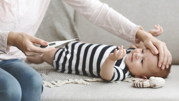 A sick baby having their temperature taken.