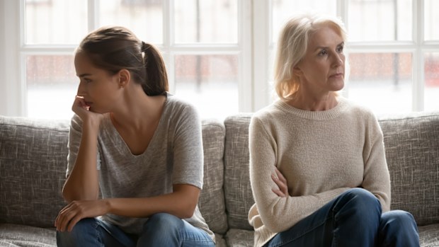 Mother and daughter sitting on couch, disgruntled after a fight.