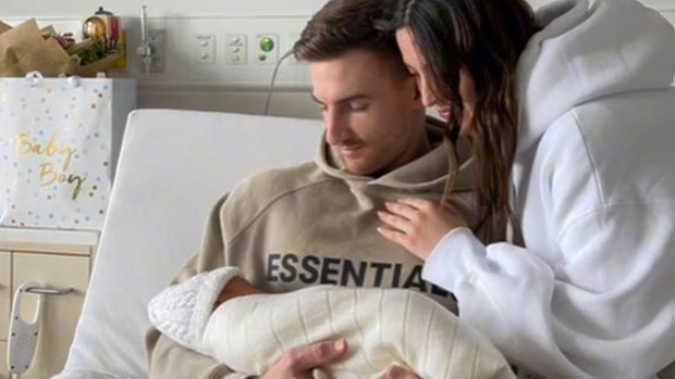 A photo of the new family, with the boyfriend sitting in the hospital bed.