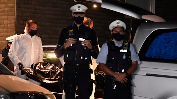 Employees of a funeral company carry a corpse to a hearse under the protection of police officers, Thursday, Sept. 3, 2020, in Solingen, Germany. 