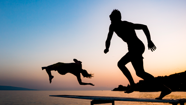 People jump into the lake Geneva on a hot summer day at sunset in Saint Saphorin, Switzerland.