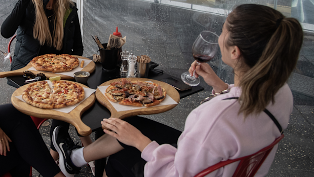 A group of women eating pizza and drinking wine at a restaurant in Bondi Beach, Sydney, Friday, May 15, 2020. 