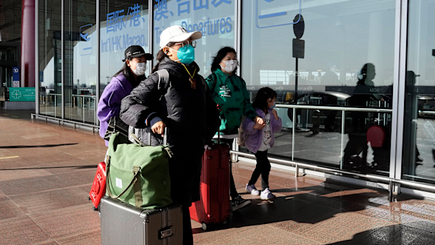 Passengers wearing masks walk through the Capital airport terminal in Beijing on Dec. 13, 2022.