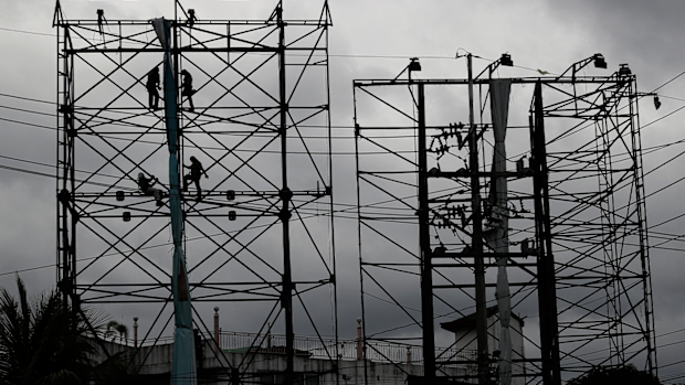 Dark clouds envelop the skies as workers fold a billboard to prepare for the coming of typhoon Vongfong, locally named Ambo, in Metro Manila, Philippines on Thursday May, 14, 2020. 