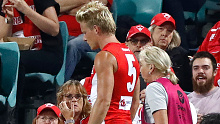 Star Sydney Swans forward Isaac Heeney in the care of a medical staffer after breaking his right hand.
