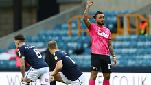 Derby's Colin Kazim-Richards raises his fist as Millwall players take a knee to boos at The Den.