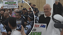 Graham Arnold is swarmed by reporters at Sydney Airport.