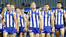 A downtrodded North Melbourne outfit trudges from the ground after its loss to Adelaide.
