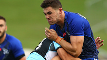 Bulldogs halfback Kyle Flanagan is tackled by a Sharks defender after kicking during an NRL trial match.