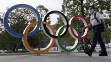 A man walks past the Olympic rings in Tokyo as the city marks one year to go until the postponed Games.