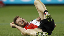 St Kilda's Darragh Joyce grimaces after being smashed by Geelong's Tom Hawkins.