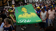 Fans hold a banner of the late Brazilian football great Pele along the route of his funeral procession from Vila Belmiro stadium to the cemetery in Santos, Brazil.