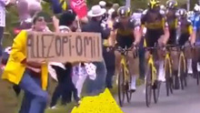 A fan holds a sign at the Tour de France, just before striking a rider and causing a massive crash.