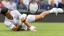Novak Djokovic stretches to play a forehand in his opening Wimbledon match against Jack Draper.