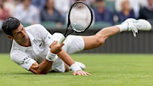 Novak Djokovic stretches to play a forehand in his opening Wimbledon match against Jack Draper.
