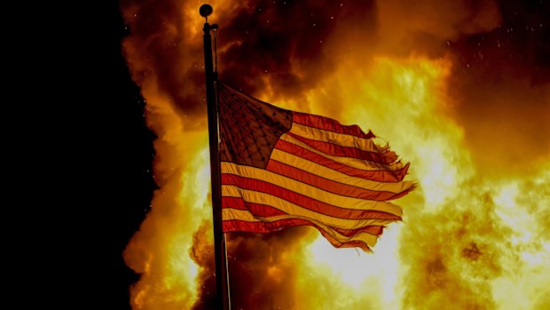 A flag flies over a department of corrections building ablaze during protests in Kenosha, Wisconsin.
