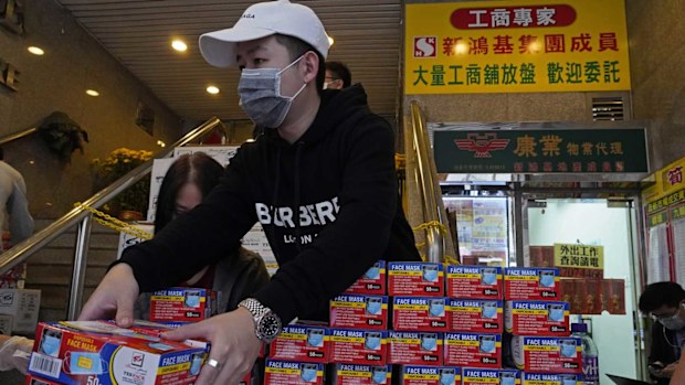 A Hong Kong shop worker puts face masks on display as the coronavirus spreads.