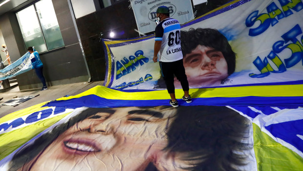Fans display flags with the face of Diego Maradona outside of Clínica Olivos
