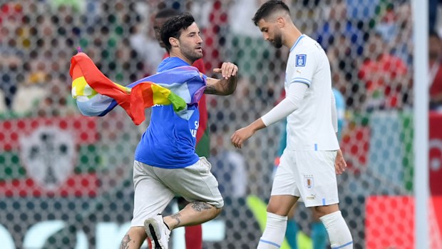 Play is stopped in the Uruguay-Portugal match as a pitch invader holding a rainbow flag invades the field.
