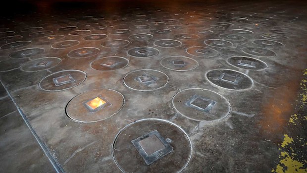 Radioactive waste sealed in large stainless steel canisters is stored under concrete in a storage building at the Savannah River Site.