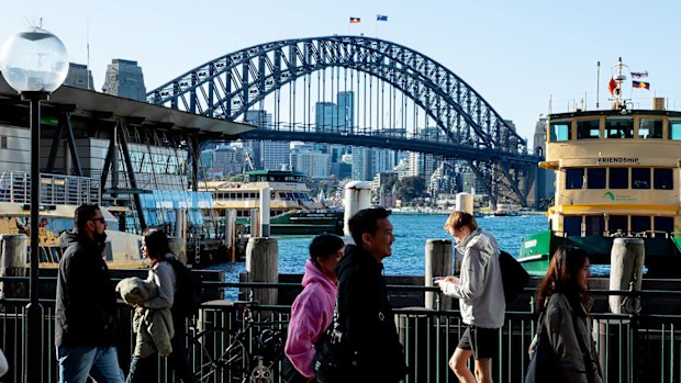 People at Circular Quay in front of the Sydney Harbour Bridge.