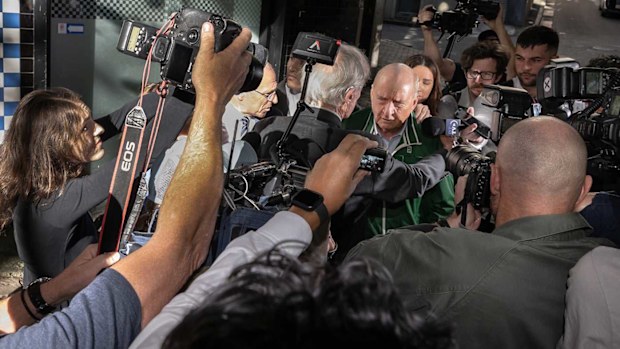 Alan Jones is surrounded by a scrum of journalists outside a Sydney police station.