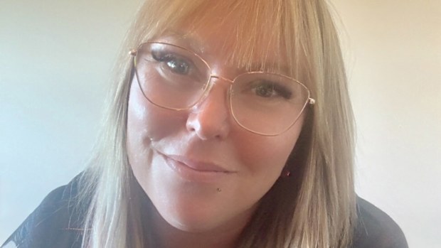 Ashlee Law, a blonde woman with glasses, smiles at the camera in a close up shot.