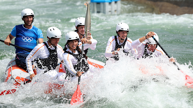Australia's Jessica Fox helps carry the Olympic Torch down the canoe slalom course at Vaires-Sur-Marne Nautical Stadium.
