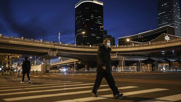 A Chinese office worker wears a protective mask as he crosses a road during rush hour in the central business district in Beijing.