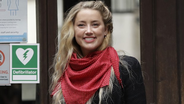 American actress Amber Heard smiles at the media as she arrives at the High Court in London, Thursday, July 23, 2020.