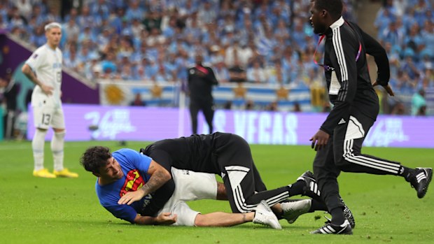 Security tackles a pitch invader during the Portugal-Uruguay match.