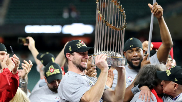 Max Scherzer #31 of the Washington Nationals holds the Commissioners Trophy 
