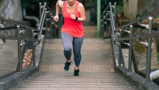 A young female athlete is running up stairs.