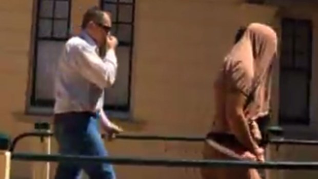 Troy Kearns, wearing a shirt over his head, is led into court. (The Chronicle)