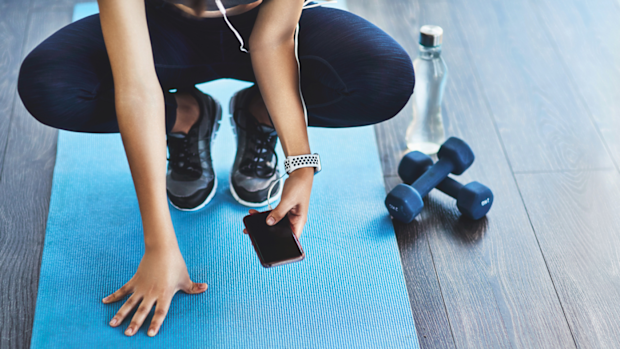 Woman working out with phone and dumbbells
