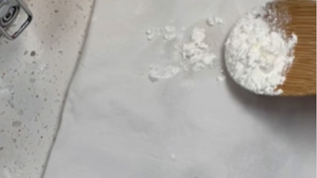 Shirt with grease stain being  removed with cornstarch or cornflour