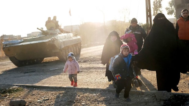 Civilians walk past Iraqi forces as they flee Mosul. (AFP)