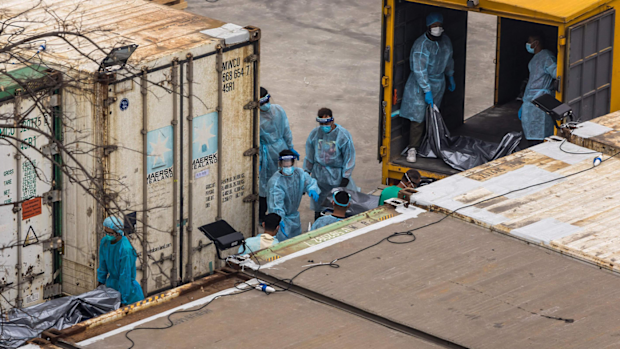 Workers move the bodies of deceased people from a truck into a refrigerated container at the Fu Shan Public Mortuary in Hong Kong on March 16, 2022, amid the city's worst-ever COVID-19 coronavirus outbreak that has seen overflowing hospitals and morgues and a frantic expansion of the city's spartan quarantine camp system.