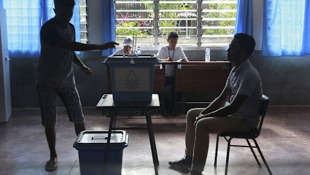 A man casts his ballot as an electoral worker, left, looks on during the presidential election at a polling station in Dili, East Timor.