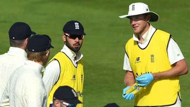Stuart Broad of England wearing PPE protective gloves speaks to his team mates during a break in play during Day Three of the 1st #RaiseTheBat Test Series between England and The West Indies