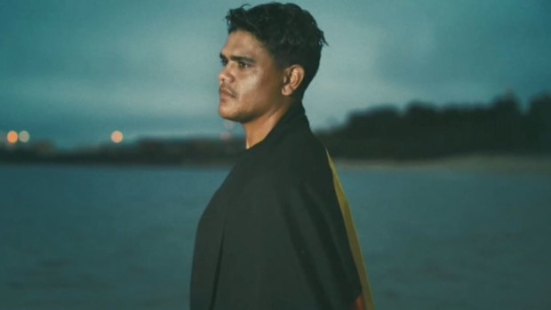 Latrell Mitchell stands with the Aboriginal flag draped around his shoulders. (NRL)